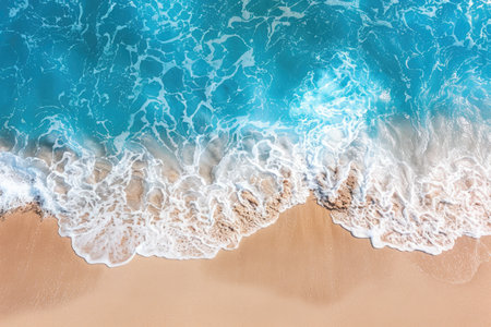 Electric blue waves crashing on sandy shore from an aerial viewの素材