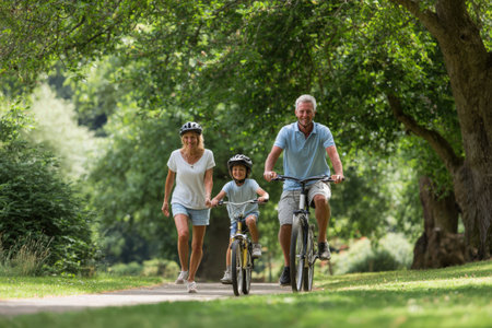 Family members are cycling in a vibrant park, surrounded by greenery, while sharing laughter and creating memorable experiences during their outdoor adventureの素材