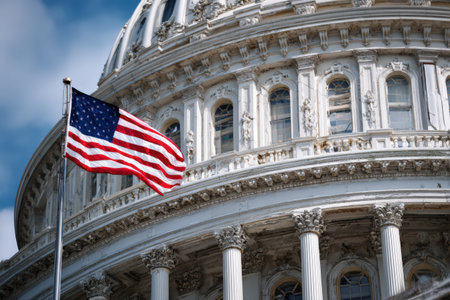 Flag of the United States flutters beside a grand government building, highlighting its architectural beauty and the significance of national symbols in civic spacesの素材
