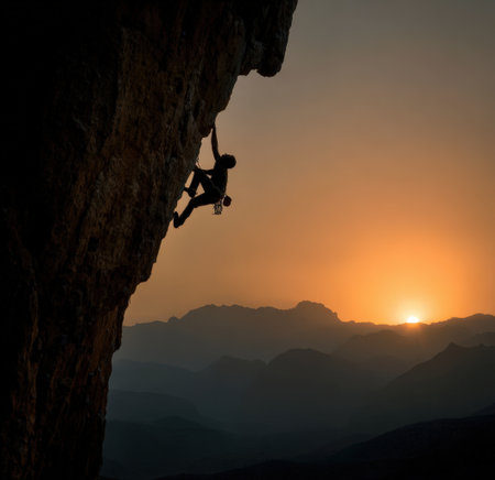 Climber ascends steep rock face during sunset, surrounded by majestic mountains, capturing the essence of adventure and the beauty of nature's landscapeの素材