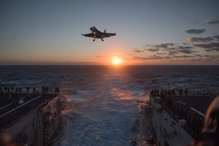 Aircraft approaches naval vessel during sunset, with crew members on deck observing the landing, highlighting the synergy of aviation and maritime activitiesの素材