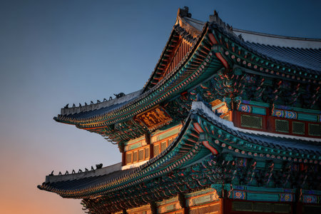 Ornate roof of traditional Asian building, highlighted by sunset glow, displaying intricate designs and vibrant colors, representing rich cultural history and artistryの素材
