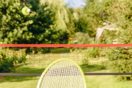 Casual badminton in garden concept with shuttlecock flying over the net and racket ready to fend offの写真素材