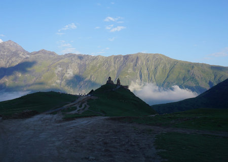 Stepantsminda Gergeti Tirnity Church View with Mountain Scape and Blue Sky at Late Afternoon