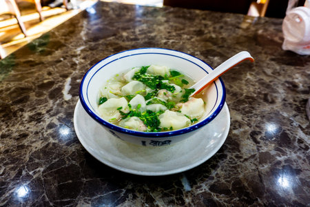 Mouthwatering Chinese Hundun Soup in a Bowl with Vegetables and Spoon