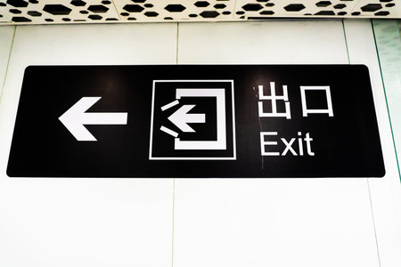 Airport White Colored Exit in English and Chinese on Black Board with Arrows