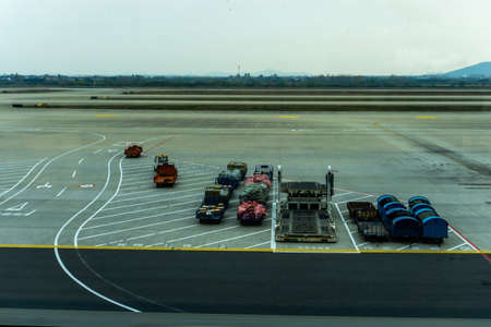 Airport Baggage Carts Parked with Luggage at Airstrip with Containersのeditorial素材