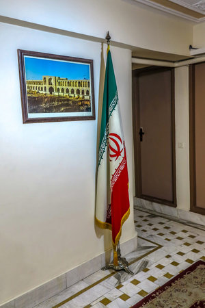 Iranian Flag Standing Still on a Flagpole in a Indoor Corridor with Image of Isfahan