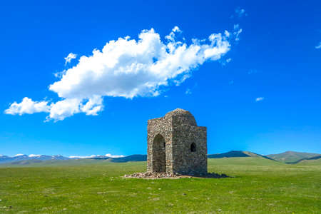 Song Kul Lake View Point with Small Mausoleum Tomb and Snow Capped Moldo Too Mountains Landscapeの写真素材