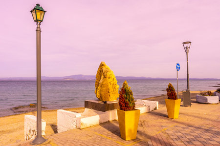 Pefkochori Promenade Street Stone Carving Relief of a Human and a Snake with Street Lights at Sunset