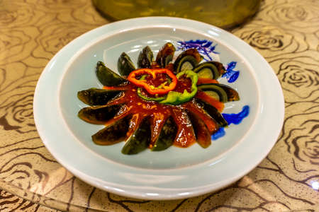 Chinese Century Egg Sliced on a Plate with Red Chili Sauceの写真素材