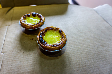 Two Chinese Mouthwatering Danta Egg Tarts on a Cardboard Box