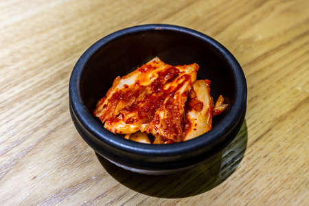 Korean Kimchi in a Small Black Bowl with Red Chili Sauceの写真素材