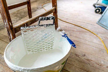 Bucket Closeup Filled with White Color Wall Painting a Paint Brush with Plastic Grid Equipment and...