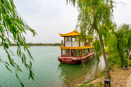Hotan Picturesque Kunlun Lake Park View of an Anchored Chinese Ship at the Shore on a Cloudy Blue...