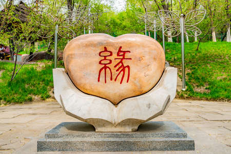 Urumqi Shuimogou Scenic Area Park Two Hands Holding a Heart Shaped Rock Sculpture on a Sunny Blue Sky Dayのeditorial素材