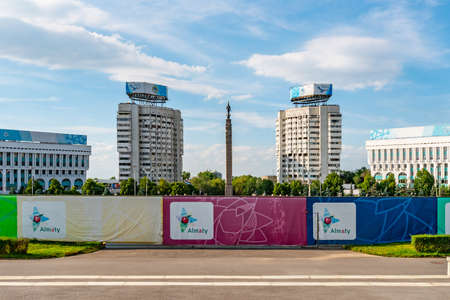 Almaty Monument of Independence Golden Warrior Statue on a High Pillar with Skyscrapers at Background on a Sunny Blue Sky Dayのeditorial素材