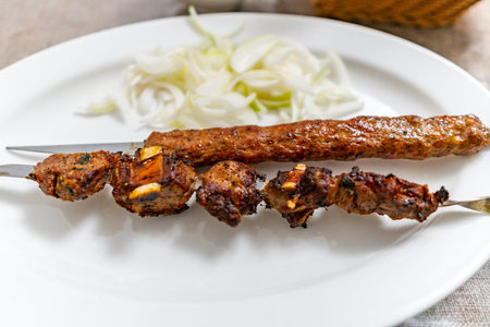 Uyghur Traditional Mouthwatering Hot Spicy Lamb and Beef Skewers with Cumin and Chopped Onions on a...