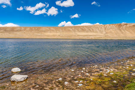 Pamir Highway M41 Lake Bulunkul with Picturesque View of Snow Capped Mountains on a Sunny Blue Sky Dayの写真素材