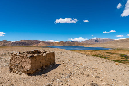Pamir Highway M41 Lake Bulunkul with Picturesque View of Abandoned Ruins on a Sunny Blue Sky Day