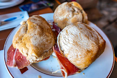 Three Traditional Mouthwatering Portuguese Pork Ham and Sheep Cheese Sandwiches on a White Plateの写真素材