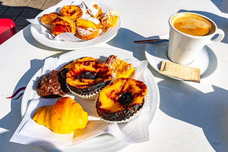 Traditional Mouthwatering Tasty Portuguese Pastel de Nata and Various Bakery Sweets on White Plates...