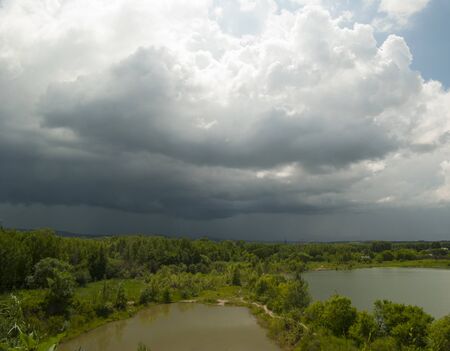 Large thunderstorm clouds, different colored lakes and dark green vegetation.の写真素材
