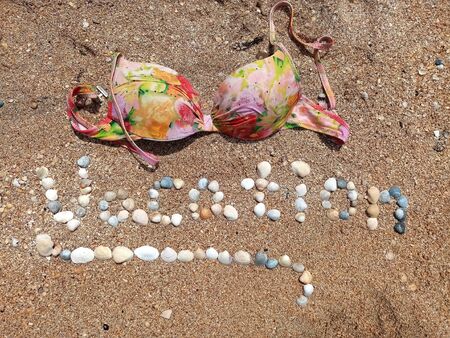 Beautiful Vacation sign formed with the shells and the brassiere laying.の写真素材
