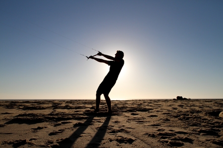 silhouette of man flying kite on beachの写真素材