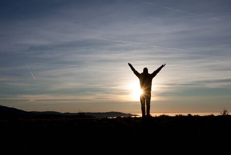 man standing in sunset on mountainの写真素材