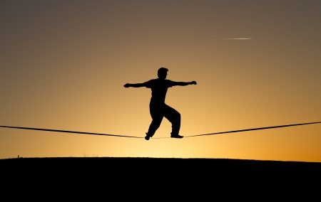 silhouette of man slacklining in sunsetの写真素材