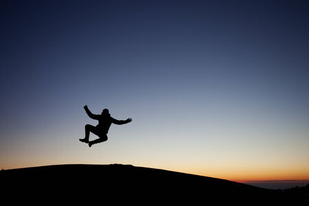 silhouetted teen heel clicking after sunsetの写真素材