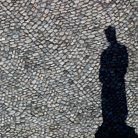 View on a shadow of a statue on cobblestonesの写真素材