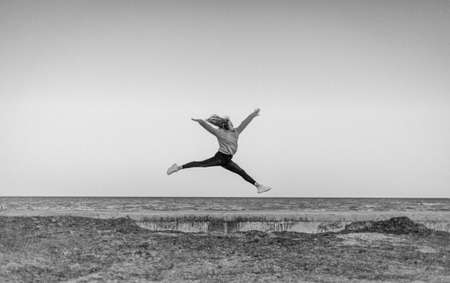 Girl gymnast jumping on the background of the seaの写真素材