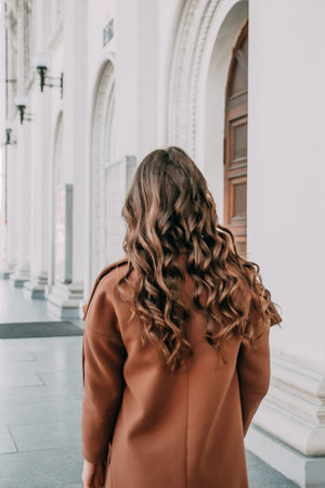 The beautiful lady with curly hair. The back view of a girl. Woman walking down the street....