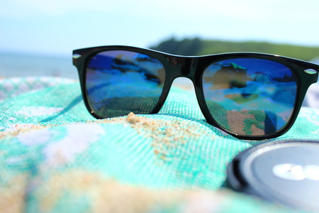 Blue sunglasses on the beach where a lot of sandの写真素材