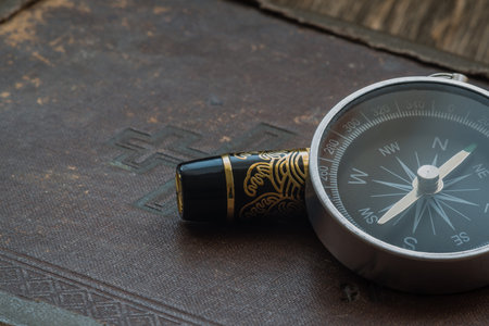 An old book and a compass on a wooden backgroundの写真素材