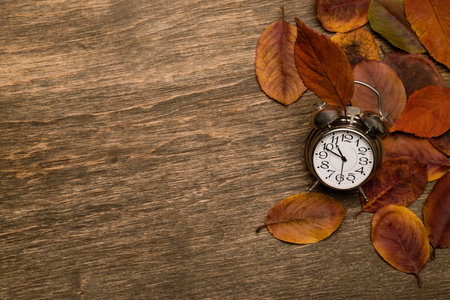 Old clock on a background of yellow leavesの写真素材