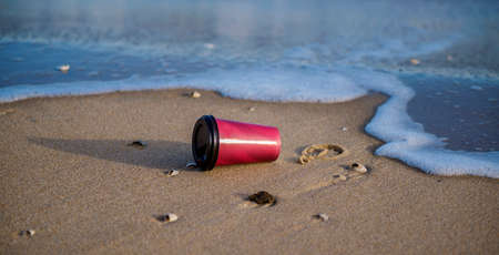 a glass with a coffee on the sandの写真素材