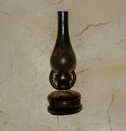 Ancient kerosene lamp on the background of an old wallの写真素材