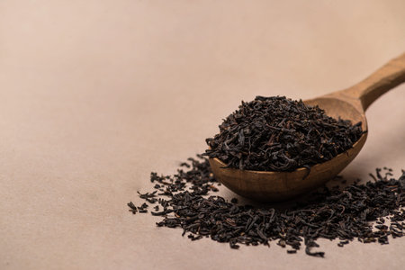 black tea in spoon close-up on paper background