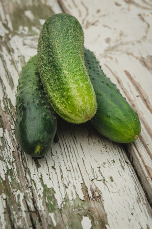 three green cucumbers lie on a wooden boardの写真素材