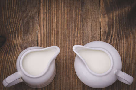 two white creamer on a wooden background / two white creamer on a wooden background. Top viewの写真素材