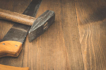 construction tools saw and hummer / construction tools saw and hummer on a wooden backgroundの写真素材