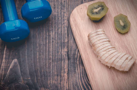 fitness background with banana, a kiwi and dumbbells /の写真素材