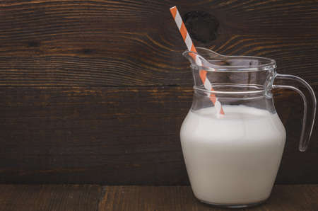 milk jug with straws on a wooden background / milk jug with straws on a wooden surfaceの写真素材