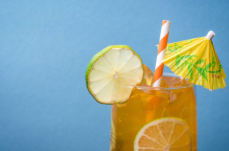 cocktail with straws and lemon on a blue background / cocktail with lemon against the background of blueの写真素材