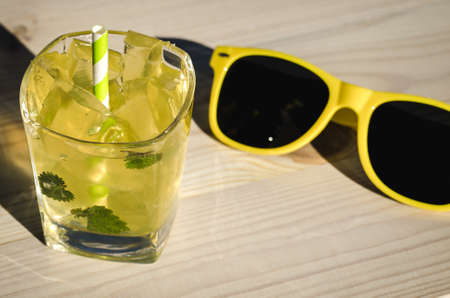 Sunglasses, yellow cocktail with mint and ice / cocktail with mint and sunglassesの写真素材