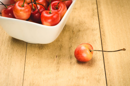 Bowl of sweet cherry and one berry / one sweet cherry and abundance of berries in a white plateの写真素材