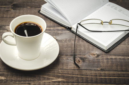 Cup of hot coffee and open bookの写真素材